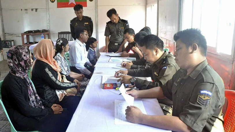 Myanmarische Militärs stellen der Rohingya-Familie Papiere aus.