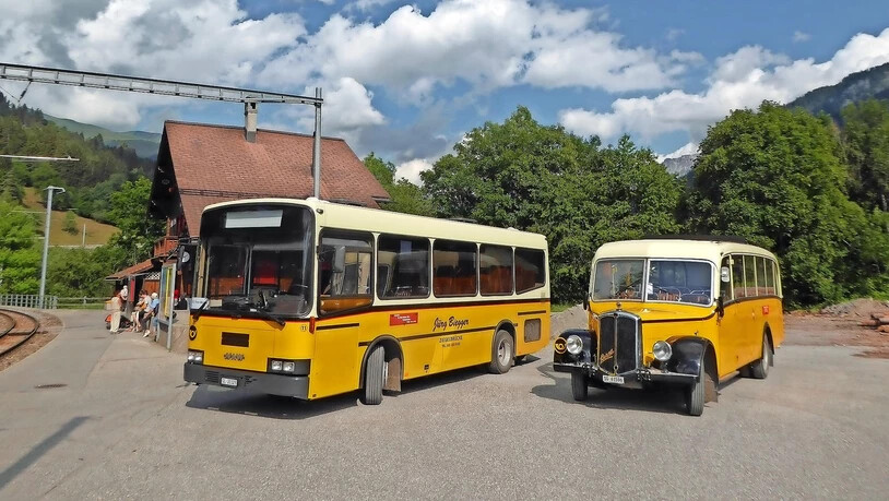 Von der Station St. Peter-Molinis RhB fahren zwei Postautos aus früheren Jahrzehnten Touristen auf die Alp.