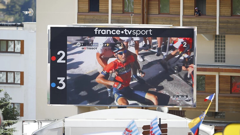 Zuschauer im Ziel verfolgen auf einem TV-Bildschirm, wie Vincenzo Nibali nach seinem Sturz im Anstieg zur Alpe d'Huez mit grossen Schmerzen am Boden sitzt