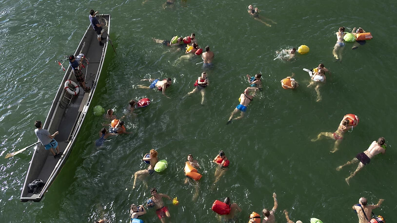 Teilnehmer des 38. Basler Rheinschwimmens werden von einem Dudelsackspieler begleitet bei ihrem Schwumm im Rhein durch die Stadt Basel am Dienstag, 14. August 2018. (KEYSTONE/Georgios Kefalas)