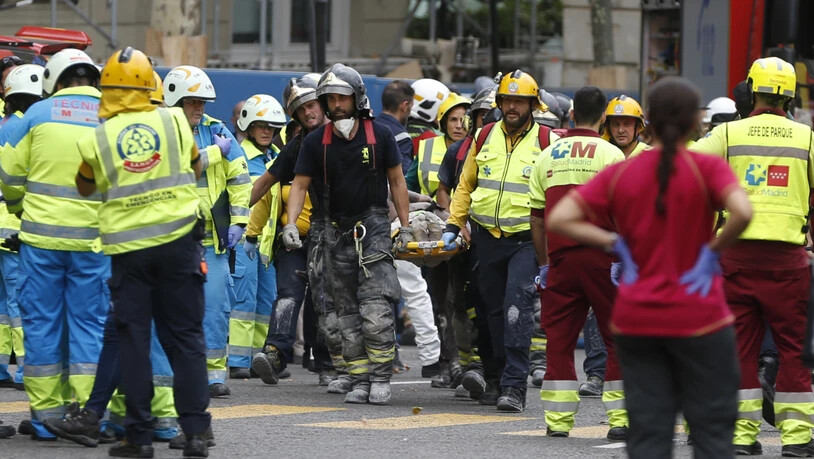 Helfer tragen einen verletzten Arbeiter vom Unfallort beim Luxushotel Ritz in Madrid weg. Der Einsturz eines Baugerüsts forderte ein Todesopfer.