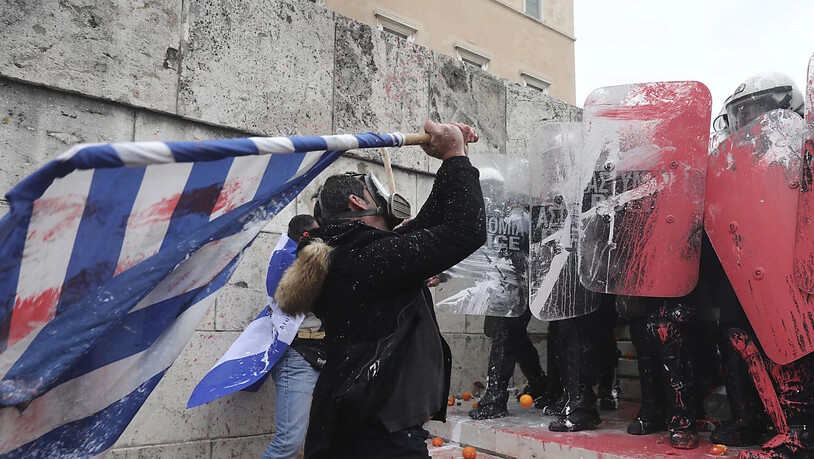 Ein Demonstrant bekämpft die Polizei mit einer griechischen Flagge. Tausende protestierten in Athen gegen den neuen Namen Nordmazedonien für den nördlichen Nachbarstaat.