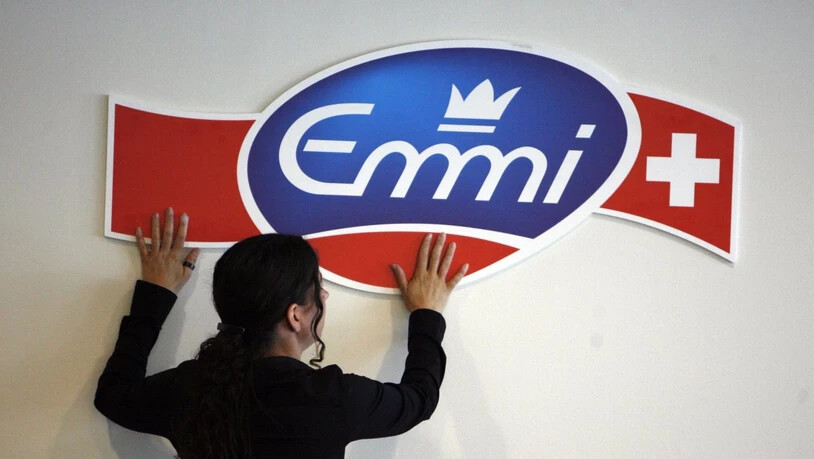 Emmi verkauft die Frisch-Service AG: Eine Mitarbeiterin des Milchverarbeiters befestigt das Logo des Unternehmens an einer Wand (Archivbild).