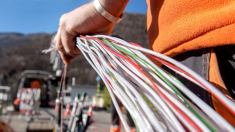 Ein Arbeiter montiert Glasfaserkabel der Swisscom. Die Comcom stützt sich bei der Preisberechnung für die Mitbenützung des Swisscom-Netzes neu auf die Kosten für Glasfaserleitungen. (Archiv)