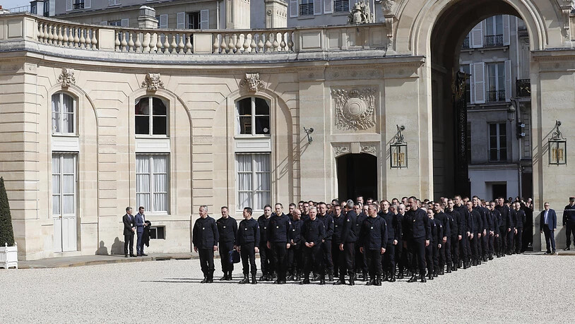 Die Feuerwehrleute warteten vor dem Präsidentenpalast in der Pariser Innenstadt, bevor sie unter Applaus von Umstehenden den Hof des Gebäudes betraten.