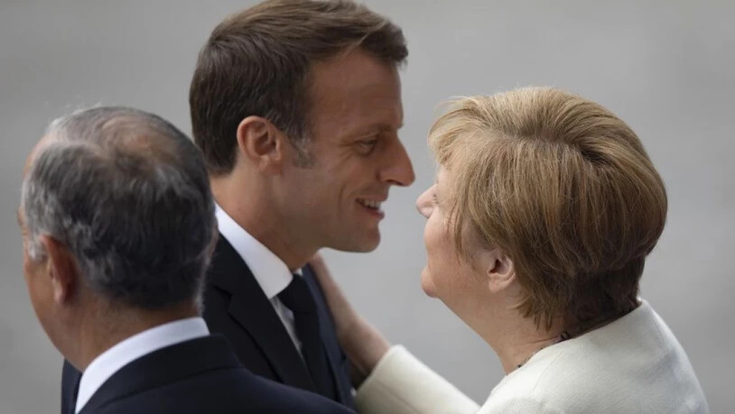 Der französische Präsident Emanuel Macron begrüsst die deutsche Bundeskanzlerin Angela Merkel vor der Parade.