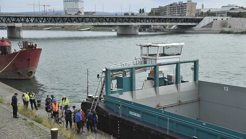 Einsatzkräfte von Polizei und Feuerwehr stehen beim Frachtschiff, das in Basel auf dem Rhein mit zwei Brücken kollidiert ist.