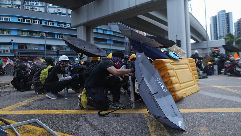 Demonstrierende in Hongkong schützen sich mit Regenschirmen.