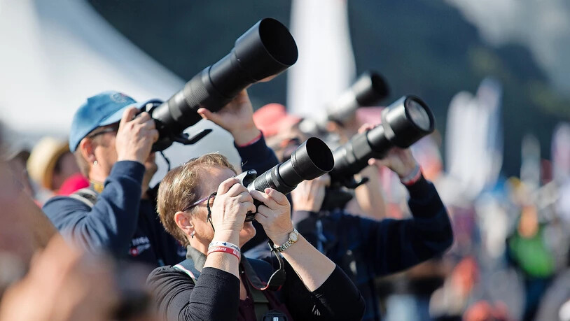 Den Kopf in  den Nacken gelegt: Aviatikfans verfolgen das Geschehen mit gezückter Kamera.