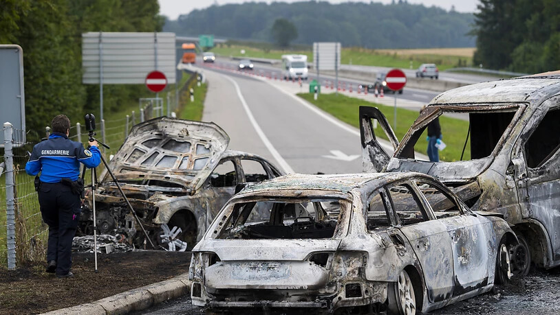 Die Polizei untersucht am Ort des Überfalls die drei verbrannten Fahrzeuge.