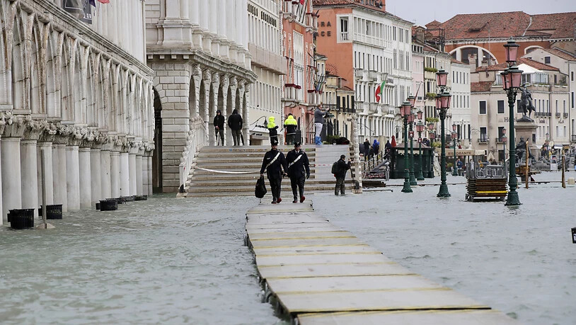 Zwei Carabinieri auf einem Steg im überfluteten Venedig.