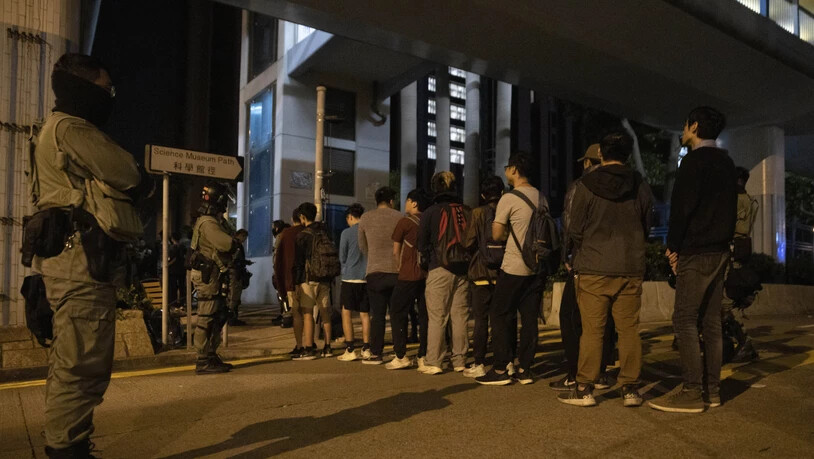 Vor der Polytechnischen Universität in Hongkong werden Studenten am Dienstagmorgen von Sicherheitskräften kontrolliert.