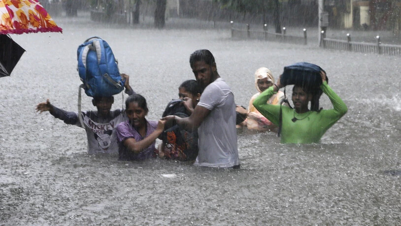 Menschen auf einer überfluteten Strasse in der indischen Metropole Mumbai. (Archivbild)