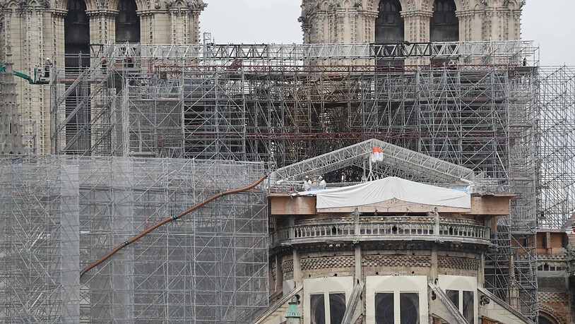 Arbeiter auf einer Plattform demontieren beschädigte Gerüstteile an der Kathedrale Notre-Dame. Foto: Ludovic Marin/AFP/dpa