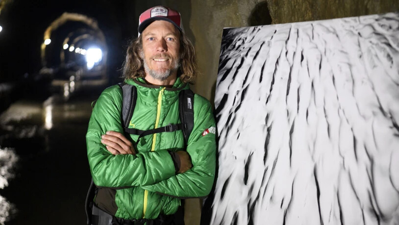 Der Fotograf David Carlier im Tälligrattunnel neben einem seiner Bilder.