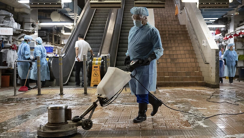 Mitarbeiter in Schutzkleidung desinfizieren einen sogenannten Nassmarkt in Hongkong. Foto: May James/ZUMA Wire/dpa