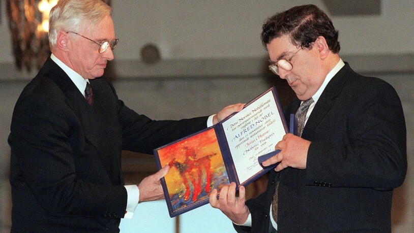 ARCHIV - John Hume (r), ehemaliger Vorsitzender der Social Democratic and Labour Party (SDLP), schaut auf das Friedensnobelpreisdiplom, das er von Francis Sejersted, damals Vorsitzender des norwegischen Friedensnobelpreiskomitees, während der…