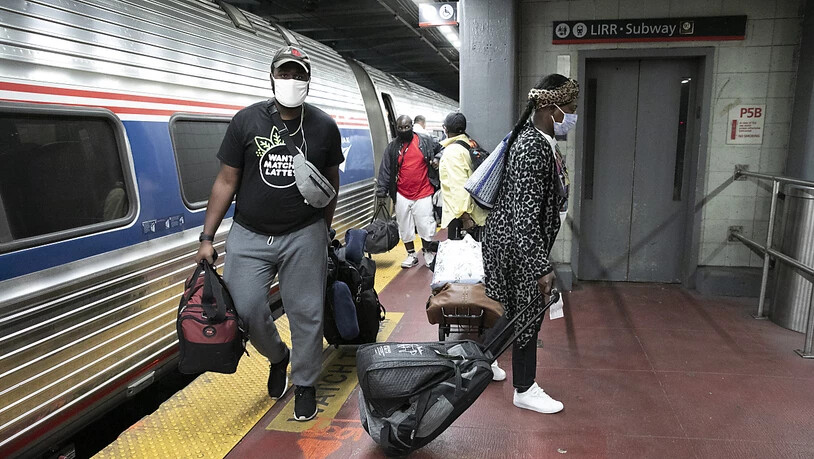 Reisende mit Mundschutz an einem Bahnhof in New York. Foto: Mark Lennihan/AP/dpa
