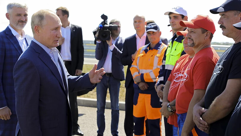 Wladimir Putin (2.v.l), Präsident von Russland, spricht bei der Eröffnungszeremonie der Tavrida-Autobahn auf der Krim, die Kertsch und Sewastopol verbindet, mit Arbeitern. Foto: Mikhail Klimentyev/Pool Sputnik Kremlin/AP/dpa