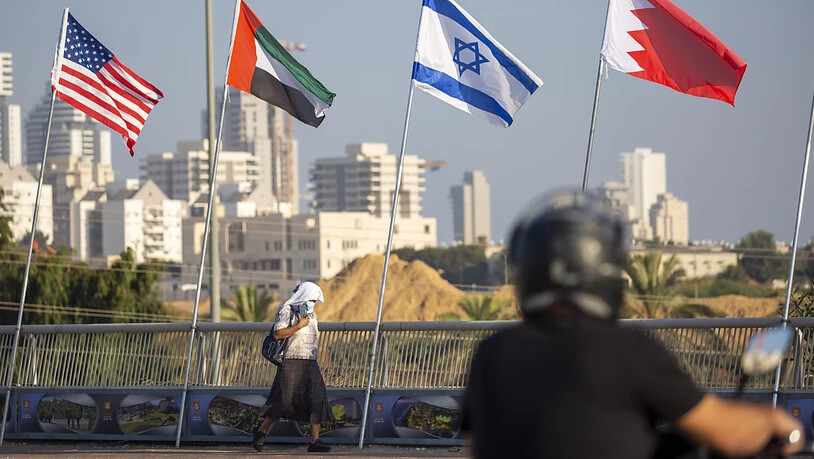 Eine Frau geht an den Flaggen der USA (l-r), der Vereinigten Arabischen Emirate, Israels und Bahrains vorbei. Foto: Ariel Schalit/AP/dpa