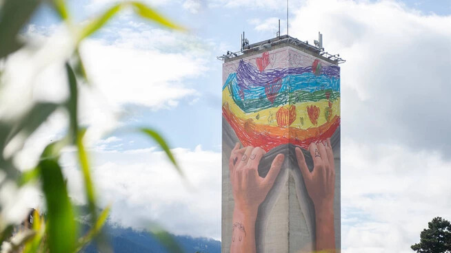Bunt und fröhlich: Der Mühleturm zeigt sein neues, kunterbuntes Sujet. Entworfen wurde das Bild von der Zweitklässlerin Mayara aus Chur. Die beiden Künstler Bane und Rips 1 haben das Motiv auf den Turm übertragen. 