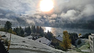 Zur Wahl der erste Schnee: Die Sonne kämpft sich durch den bedeckten Himmel über dem St. Moritzersee.