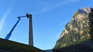 Ein Spegler montiert zuoberst am Schornstein auf dem  Möbeli-Areal in Glarus einen Kupferring samt Biltzableiter.