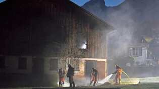 Mottbrand unter Kontrolle: Feuerwehrleute holen schwelendes Heu aus dem Stall und löschen die Glut. 