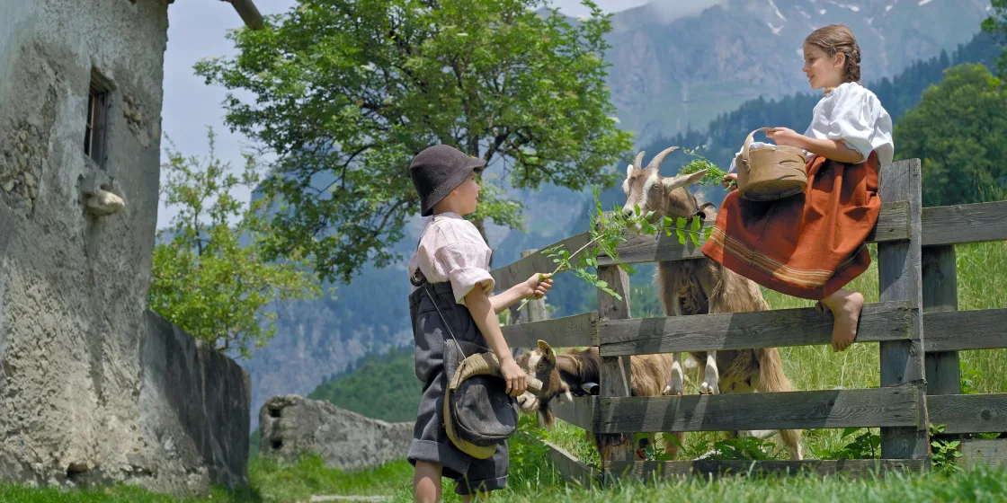Die Geschichte aufleben lassen: Zwei Kinder, als Heidi und Peter verkleidet, füttern die Ziegen auf dem Gelände des Heididorfs.