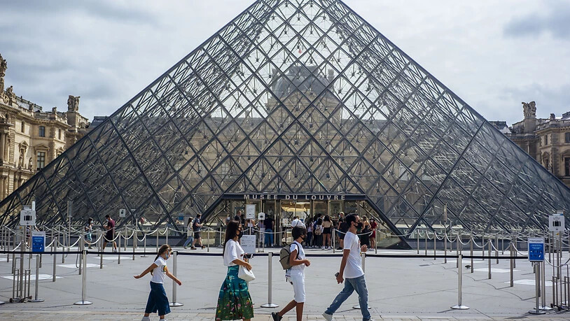 ARCHIV - Eine Familie mit Schutzmasken geht am Louvre vorbei. (zu dpa "Corona-Krise: Frankreich kommt seinen großen Museen zu Hilfe") Foto: Kamil Zihnioglu/AP/dpa