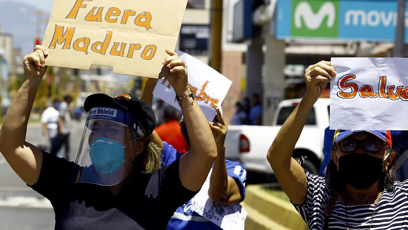 Eine Frau mit Mund-Nasen-Schutz hält bei einer Demonstration in Valencia ein Plakat mit der Aufschrift «Fuera Maduro» (Raus mit Maduro) in die Höhe. Foto: Juan Carlos Hernandez/ZUMA Wire/dpa
