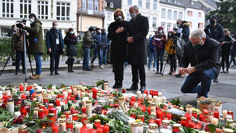 Malu Dreyer (SPD), Ministerpräsidentin von Rheinland-Pfalz, und ihr Ehemann Klaus Jensen stehen vor Blumen und Kerzen, die vor der Porta Nigra im Gedenken der Opfer der Amokfahrt eines 51-jährigen Mannes durch die Innenstadt niedergelegt wurden. Foto:…