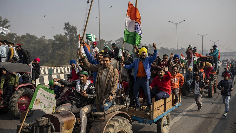 Indische Landwirte versammeln sich auf Traktoren zu einem Protest gegen neue Landwirtschaftsgesetze, während das Land zur gleichen Zeit den «Tag der Republik» mit einer Militärparade feiert. Foto: Altaf Qadri/AP/dpa