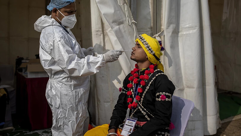 ARCHIV - Ein Mitarbeiter des Gesundheitswesen in Indien entnimmt einem Mann einen Abstrich für einen Corona-Test. Foto: Altaf Qadri/AP/dpa