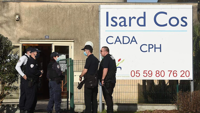 Polizeibeamte stehen vor dem Eingang des Isard Cos Aufnahmezentrums für Geflüchtete (CADA), in dem ein Mann mit einem Messer getötet worden sein soll. Foto: Gaizka Iroz/AFP/dpa