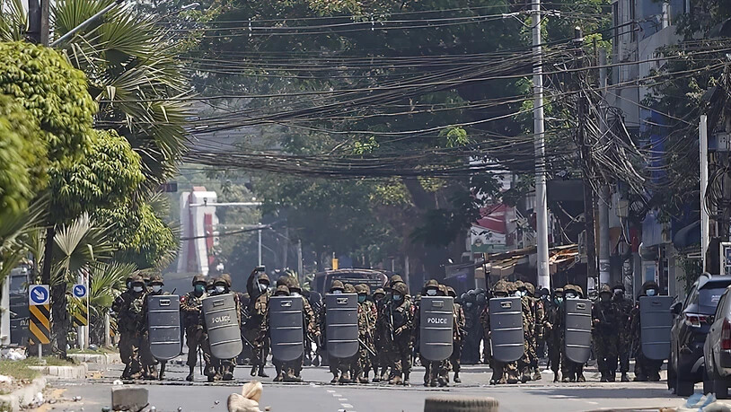 Einsatzkräfte des Militärs mit Schutzschilden bewegen sich während eines Protests in Rangun eine Straße hinauf. Foto: Uncredited/AP/dpa