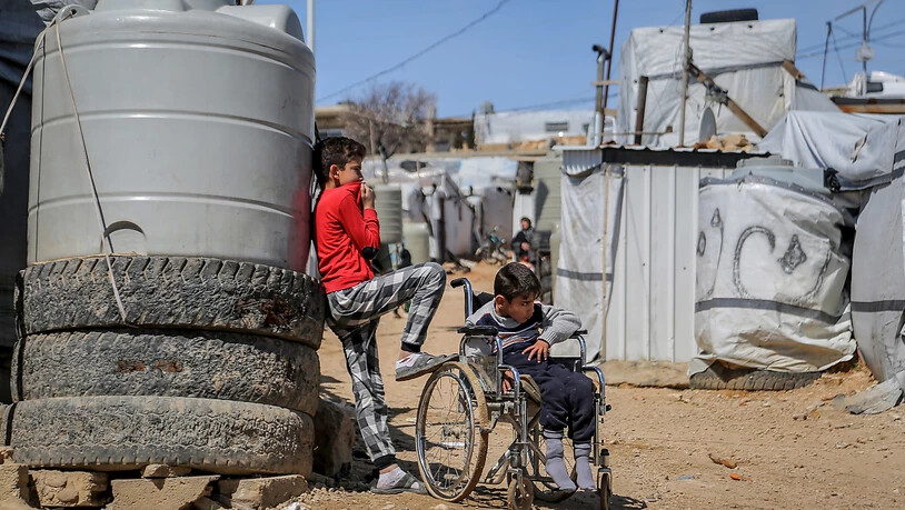 Ein syrischer Junge steht neben seinem Bruder, der im Rollstuhl sitzt, im Flüchtlingslager Barra nordöstlich der libanesischen Hauptstadt Beirut. Foto: Marwan Naamani/dpa