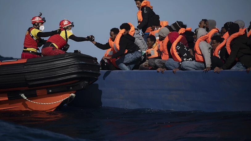 ARCHIV - Migranten aus Eritrea, Ägypten, Syrien und dem Sudan werden an Bord eines Holzbootes im Mittelmeer etwa 110 Meilen nördlich von Libyen darauf, von Helfern der spanischen NGO «Open Arms» unterstützt. (Illustration zu dpa: "Hilfsorganisation Open…