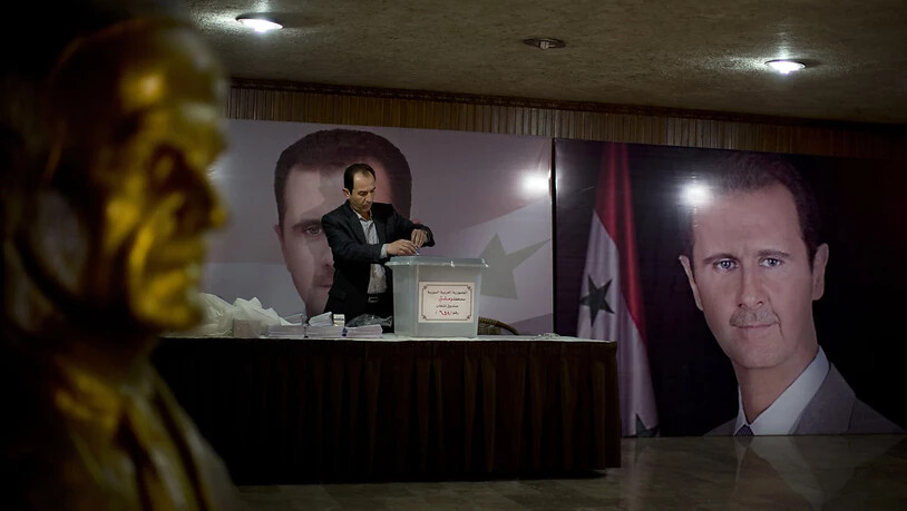 ARCHIV - Ein Wahlhelfer steht in einem Wahllokal mit Plakaten von Präsident Baschar al-Assad .  Die Führung des Bürgerkriegslandes Syrien plant Ende kommenden Monats eine Präsidentschaftswahl. Foto: Hassan Ammar/AP/dpa