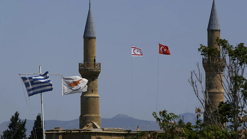 Griechische und zypriotische Flaggen flattern im Wind im südlichen Teil. Währenddessen im Norden, im türkisch besetzten Gebiet, eine türkische und eine türkisch-zypriotische Flagge auf einem Minarett der Selimiye-Moschee in der geteilten Hauptstadt…