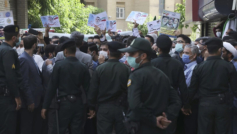 Unterstützer des ehemaligen Präsidenten Ahmadinejad halten Plakate mit seinem Konterfei, während er sich im Innenministerium als Kandidat für die Präsidentschaftswahlen am 18. Juni registriert. Polizisten hindern die Unterstützer daran sich dem Gebäude…