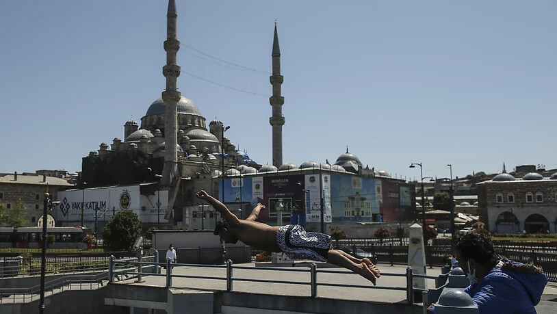 Vor dem Hintergrund der historischen Neuen Moschee springt ein Jugendlicher von der Galata Brücke in den Bosporus. Foto: Emrah Gurel/AP/dpa