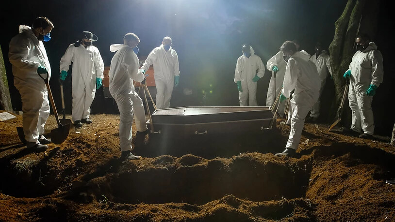 ARCHIV - Mitarbeiter des Friedhofs Vila Formosa, dem größten in Lateinamerika, tragen einen Sarg, um eine an Covid-19 verstorbene Person zu beerdigen. Aufgrund der hohen Sterbefälle, arbeiten die Mitarbeiter auch während der Nacht. Foto: Lincon Zarbietti…