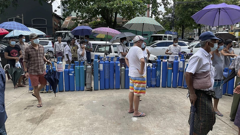Menschen stehen mit ihren Sauerstoffflaschen vor einer Nachfüllstation in Yangon. Myanmar leidet unter einem Mangel an Sauerstoffkapazitäten, während ein Anstieg der Corona-Fallzahlen zu verzeichnen ist. Foto: Uncredited/AP/dpa