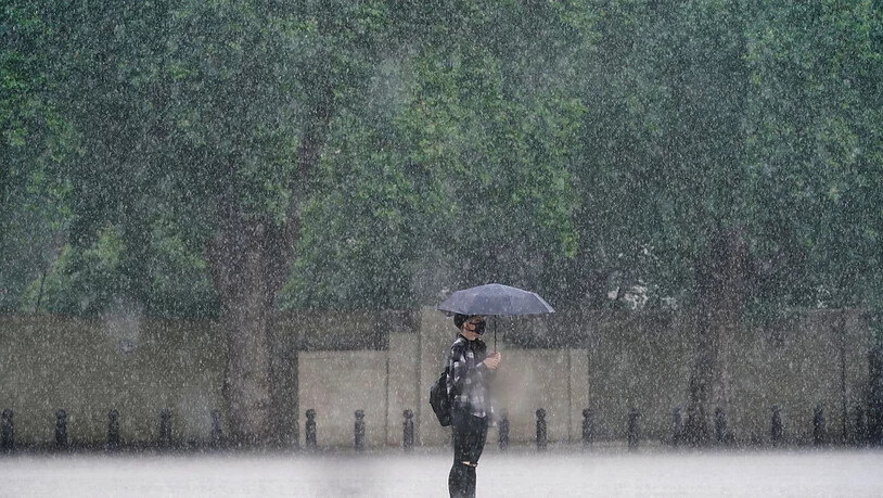 Eine Frau in London schützt sich mit einem Schirm vor dem starken Regen. Foto: Victoria Jones/PA Wire/dpa