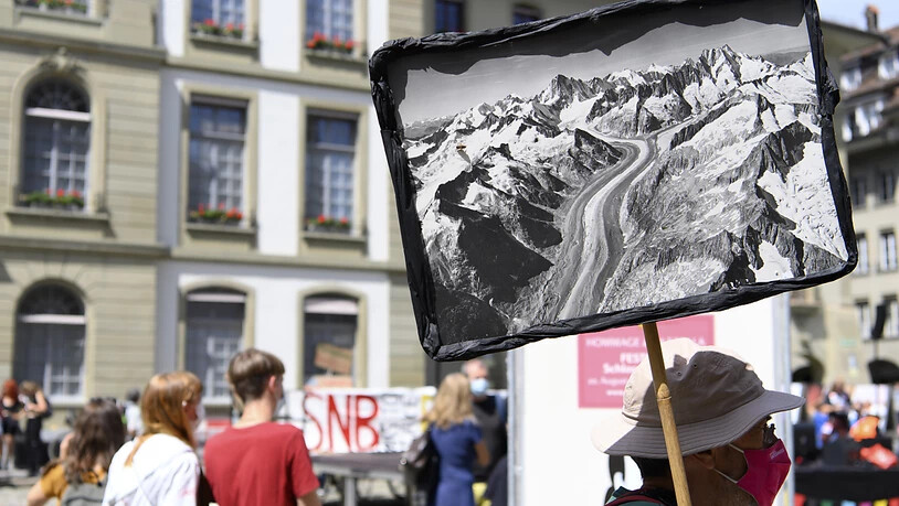 Ein Aktivist protestiert mit Plakat wähend einer Klimademonstration von "Rise Up For Change"auf dem Münsterplatz in Bern