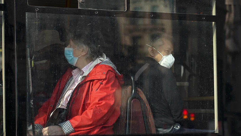 Menschen tragen Mund-Nasen-Schutz, während sie in einem Bus in London sitzen. Foto: Alberto Pezzali/AP/dpa
