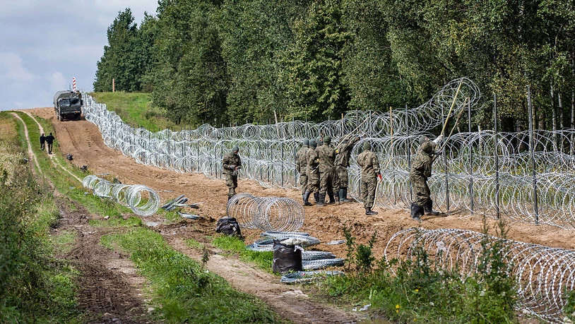 ARCHIV - Polnische Soldaten errichten einen Stacheldrahtzaun entlang der polnisch-belarussischen Grenze. Nach Einschätzung von Menschenrechtlern verschärft sich die Lage für Migranten auf dem Weg Richtung EU immer mehr. Das teilte die belarussische…