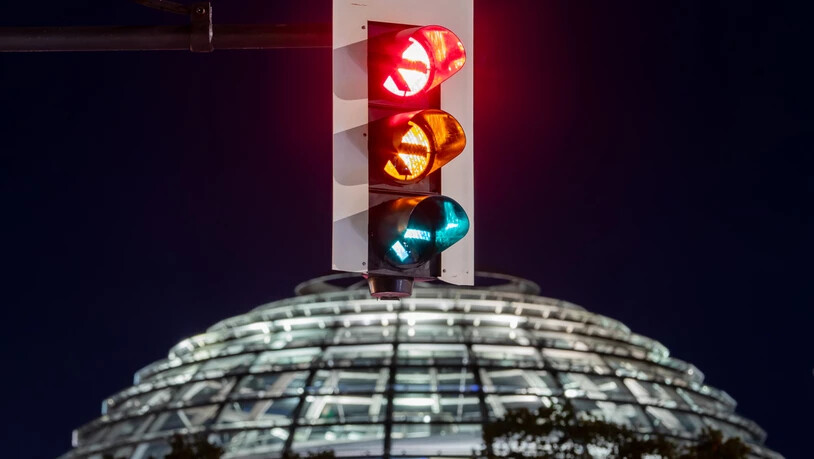 dpatopbilder - Eine Ampel vor der Kuppel des Reichstagsgebäudes leuchtet in allen drei Phasen. Einen Monat nach der Bundestagswahl steigen SPD, Grüne und FDP in die Detailverhandlungen über die Bildung einer gemeinsamen Regierung ein. Foto: Christoph…