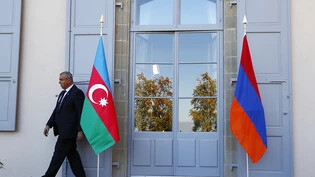 Ein Sicherheitsbeamter geht an einer aserbaidschanischen (Links) und einer armenischen Flagge vor Beginn von Gesprächen zwischen den Konfliktländern 2017 in Genf vorbei. (Archivbild)